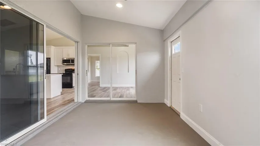 Unfurnished room with hardwood / wood-style floors and vaulted ceiling