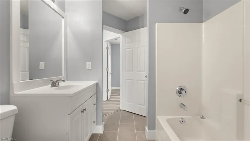 Full bathroom featuring tile patterned flooring, vanity, toilet, and  shower combination