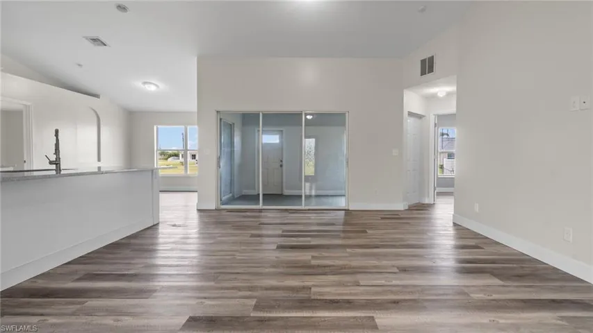 Unfurnished room with dark wood-type flooring and lofted ceiling