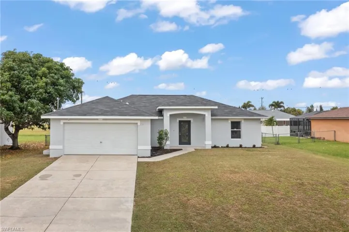 Ranch-style house featuring a front lawn and a garage