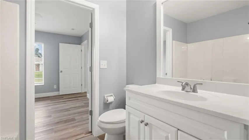Bathroom with vanity, hardwood / wood-style flooring, toilet, and a shower