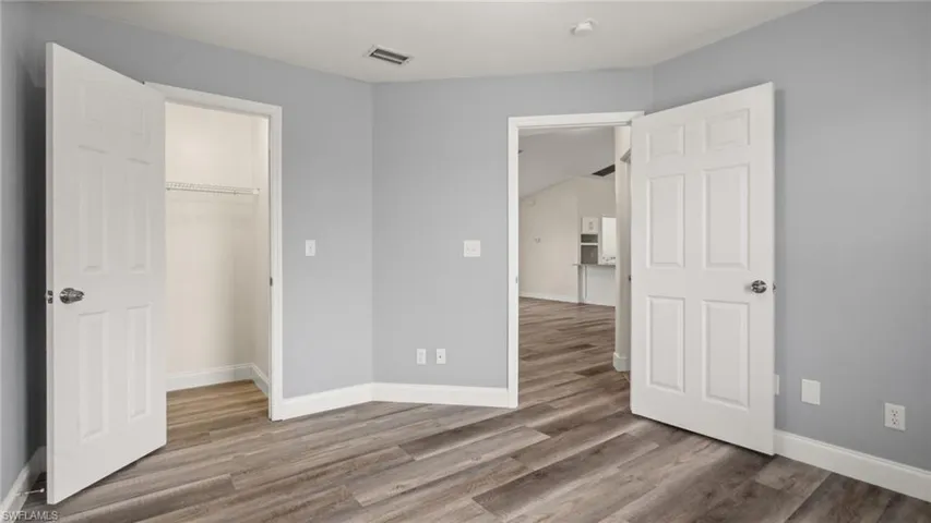 Unfurnished bedroom with a spacious closet, hardwood / wood-style flooring, and a closet