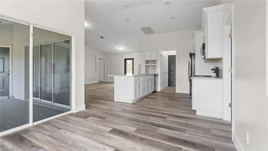 Kitchen featuring white cabinetry, kitchen peninsula, light hardwood / wood-style flooring, and sink