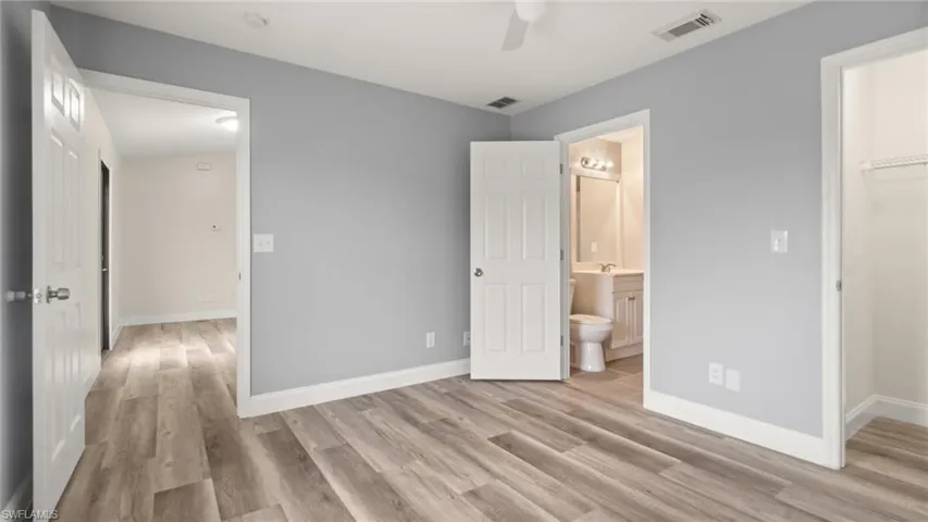 Unfurnished bedroom featuring a closet, a walk in closet, connected bathroom, light hardwood / wood-style floors, and ceiling fan