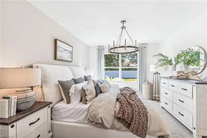 Bedroom featuring light carpet and a chandelier