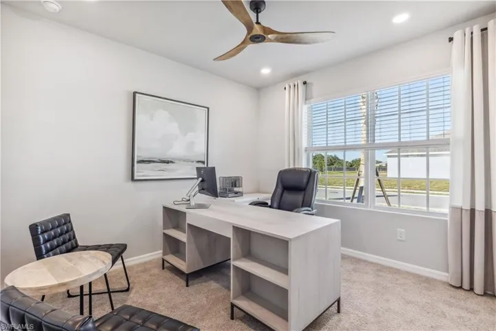 Office with light carpet and ceiling fan