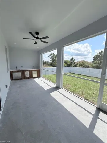 Unfurnished sunroom with a ceiling fan and a patio