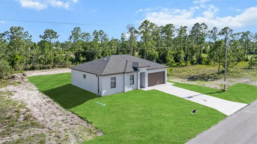 View of front of house featuring driveway, a front yard, stucco siding, an attached garage, and a shingled roof