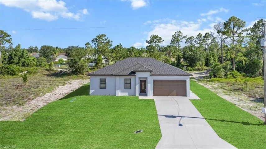 View of front facade featuring an attached garage, stucco siding, a front yard, and concrete driveway