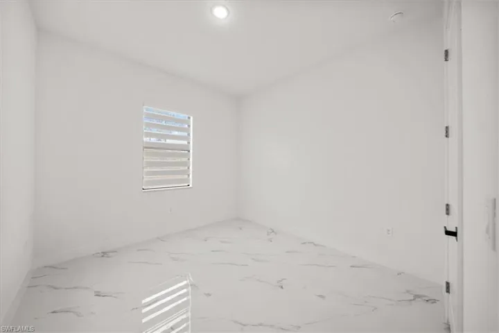 Empty room with marble look tile flooring and recessed lighting