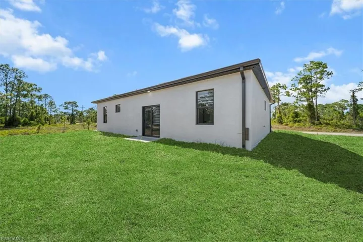 Rear view of property featuring stucco siding and a lawn