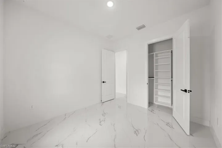 Unfurnished bedroom featuring light marble finish flooring, recessed lighting, a closet, and a spacious closet