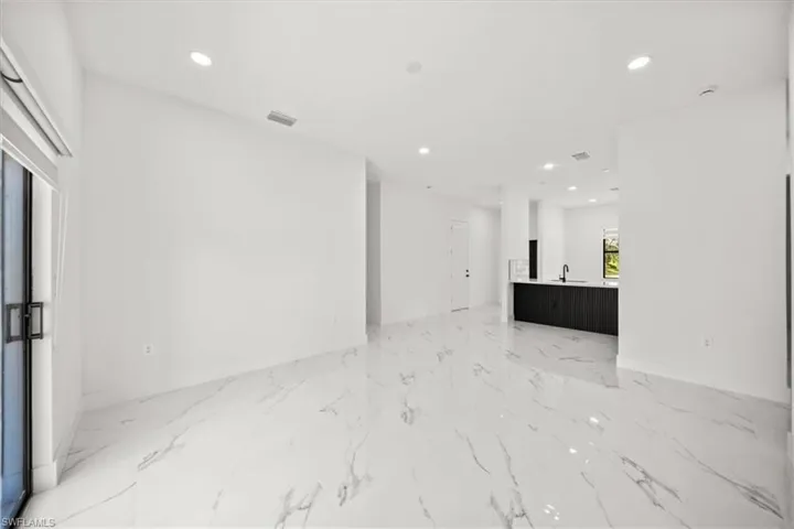 Unfurnished living room featuring light marble finish floors and recessed lighting