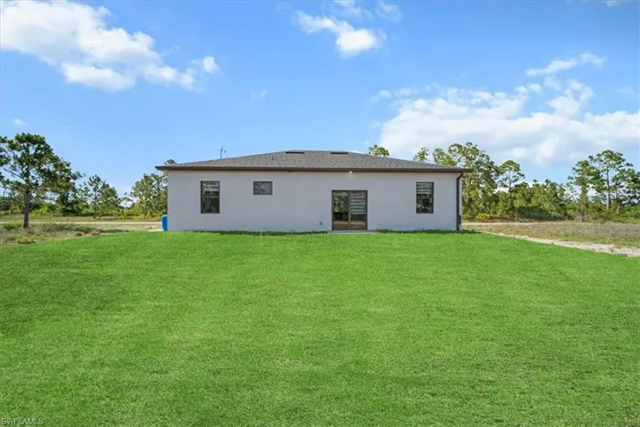 Back of property with stucco siding and a yard