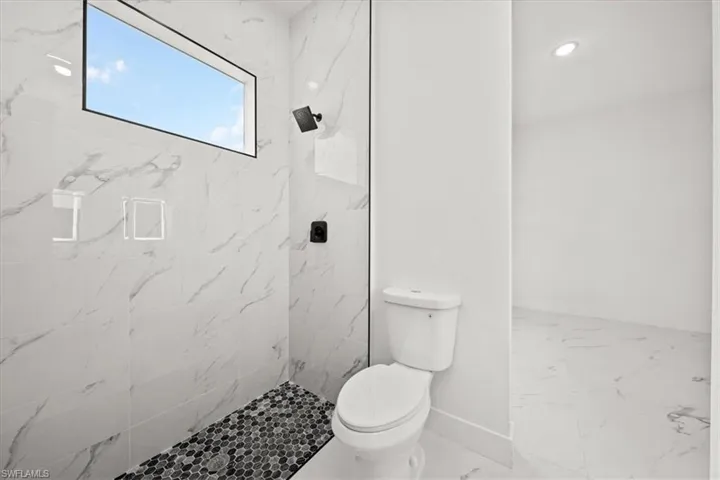 Bathroom featuring tiled shower and marble look tile flooring