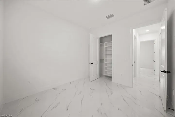 Unfurnished bedroom featuring marble finish floors, a spacious closet, and a closet