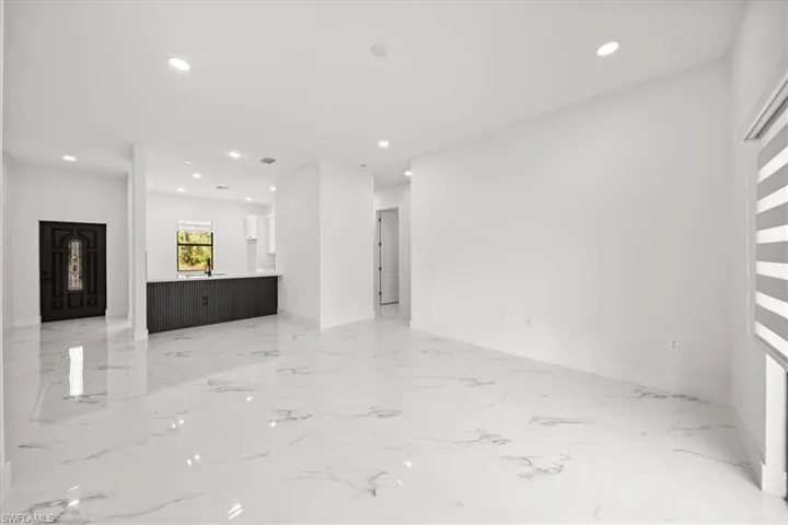 Unfurnished living room featuring light marble finish flooring and recessed lighting