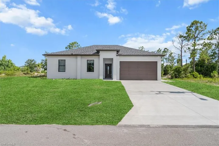 Prairie-style house featuring stucco siding, a garage, a front yard, and driveway