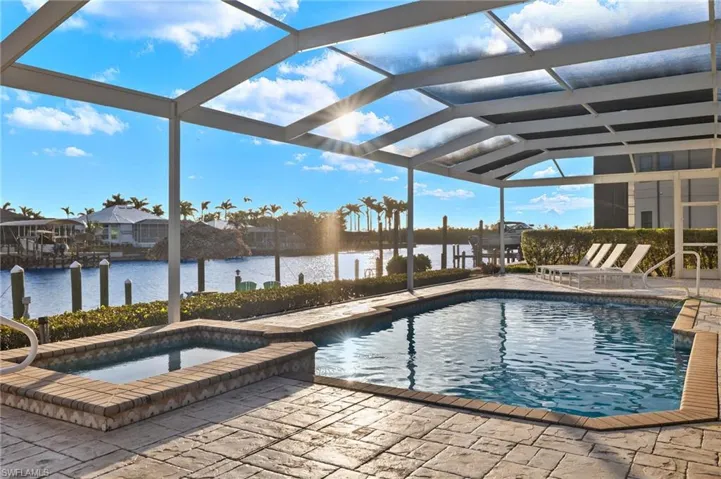 View of pool featuring a lanai, an in ground hot tub, a water view, and a patio