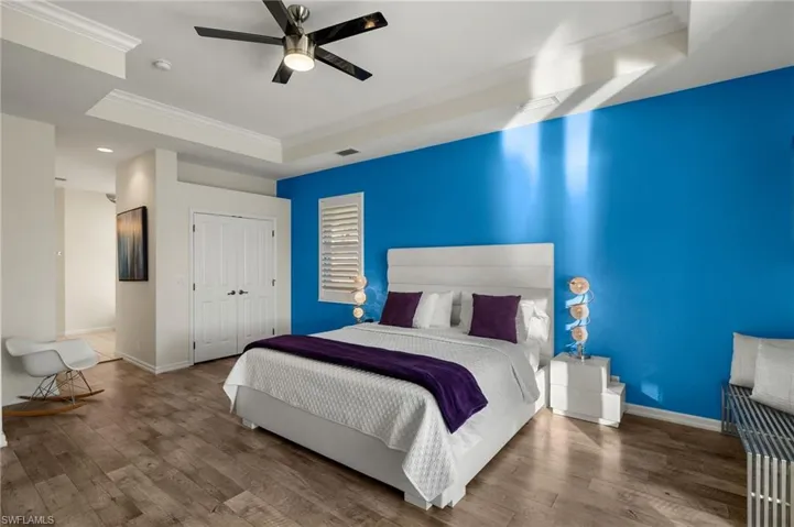 Bedroom with a raised ceiling, ceiling fan, crown molding, hardwood / wood-style floors, and a closet