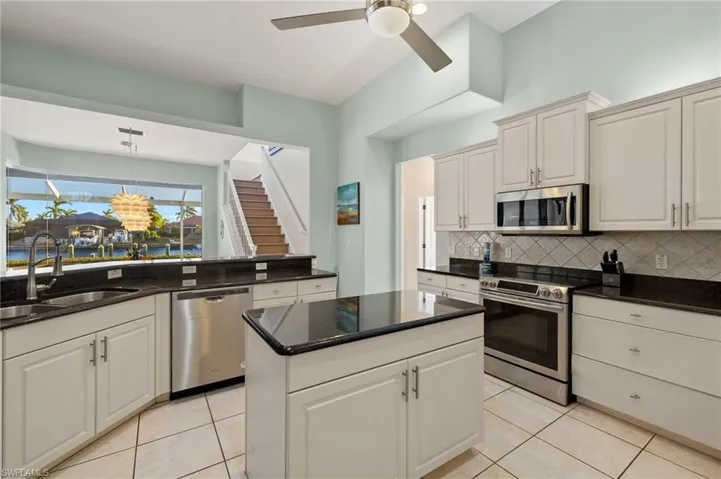 Kitchen with stainless steel appliances, white cabinetry, and sink