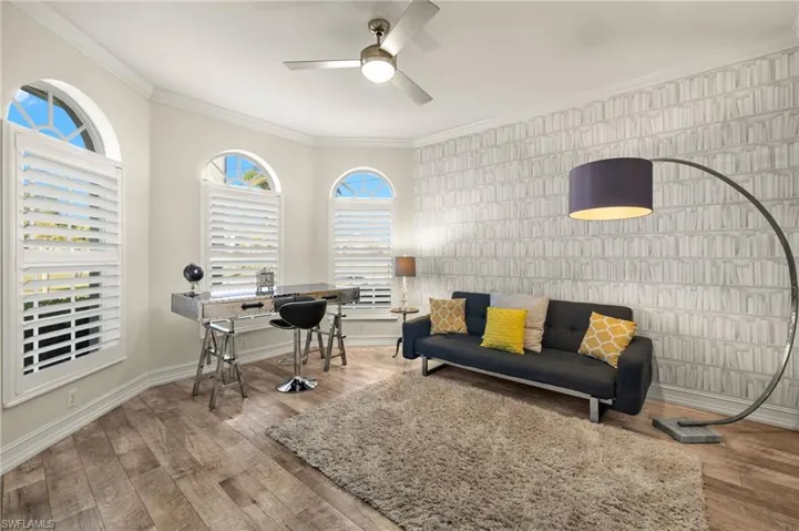 Living room with ceiling fan, ornamental molding, tile walls, and hardwood / wood-style flooring
