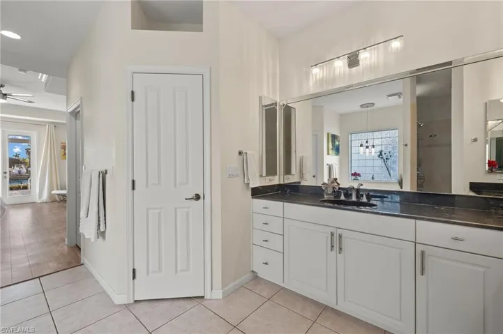Bathroom featuring tile patterned floors, ceiling fan, a shower, and vanity