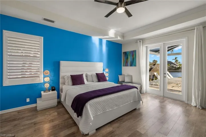 Bedroom featuring dark wood-type flooring, access to outside, a water view, crown molding, and ceiling fan