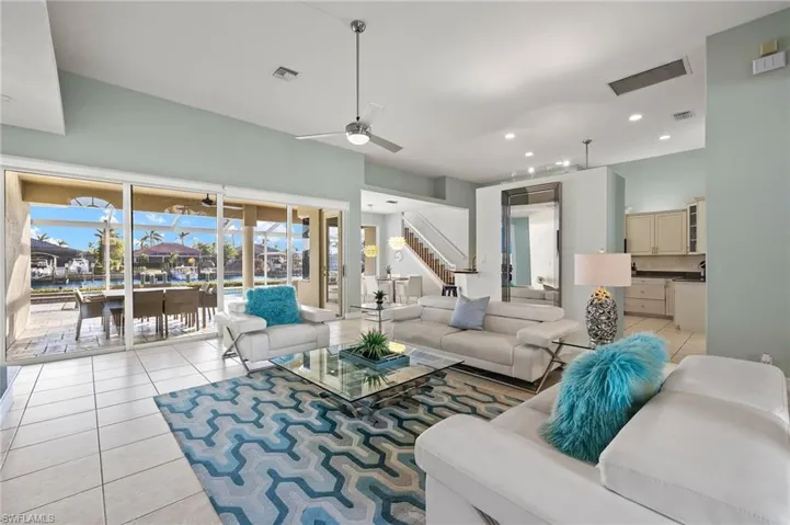 Living room with light tile patterned floors, a wealth of natural light, and ceiling fan