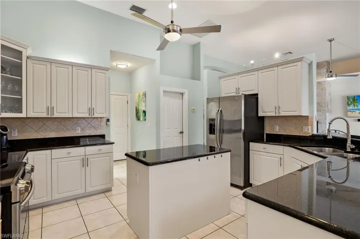 Kitchen with white cabinets, sink, ceiling fan, light tile patterned floors, and appliances with stainless steel finishes