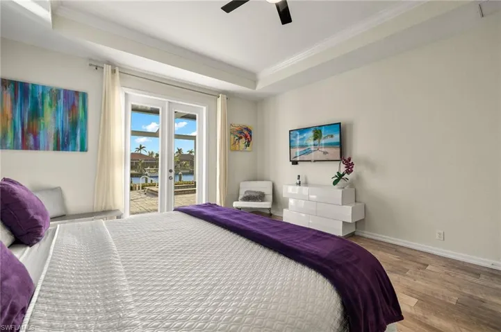 Bedroom with access to outside, a raised ceiling, ceiling fan, crown molding, and hardwood / wood-style floors
