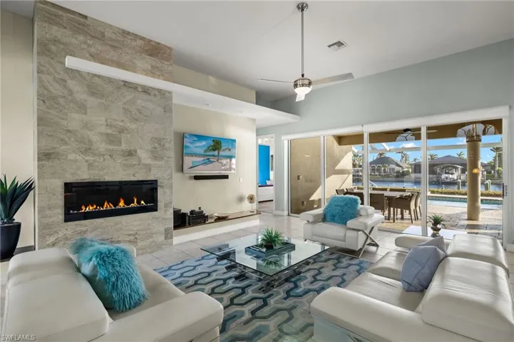 Living room featuring ceiling fan, light tile patterned flooring, and a tiled fireplace