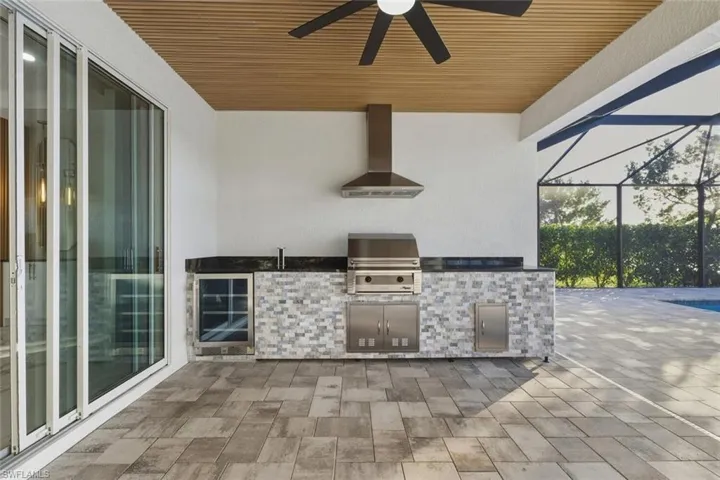 View of patio / terrace featuring a lanai, beverage cooler, ceiling fan, area for grilling, and a sunroom