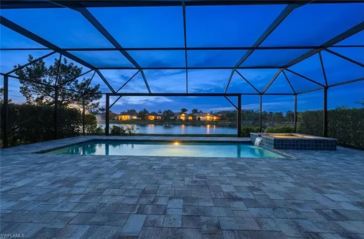 View of pool featuring glass enclosure, a sunroom, a patio area, a pool with connected hot tub, and a water view