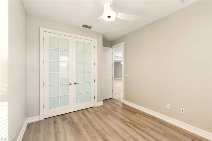 Unfurnished bedroom with light wood-type flooring, ceiling fan, a closet, and french doors