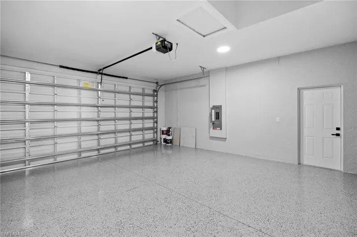 Garage with electric panel, a garage door opener, and recessed lighting