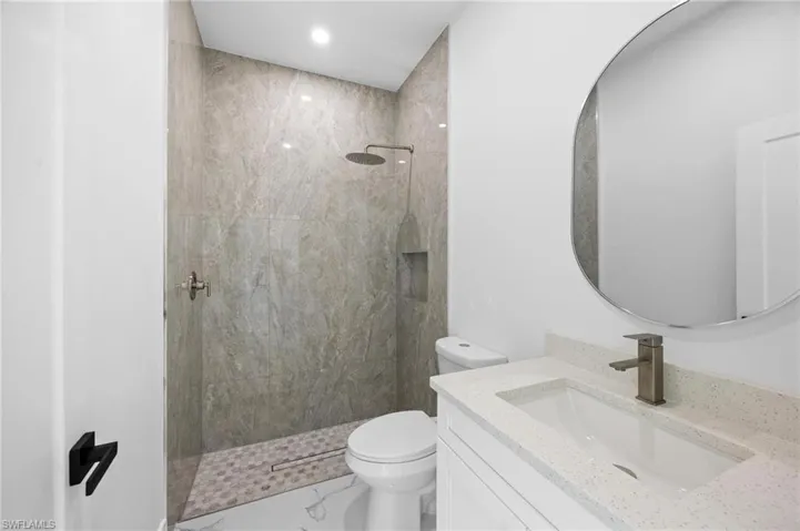 Bathroom featuring walk in shower, vanity, and marble finish floors