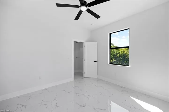 Unfurnished bedroom with light marble finish floors and ceiling fan