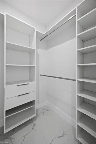 Spacious closet featuring light marble finish floors