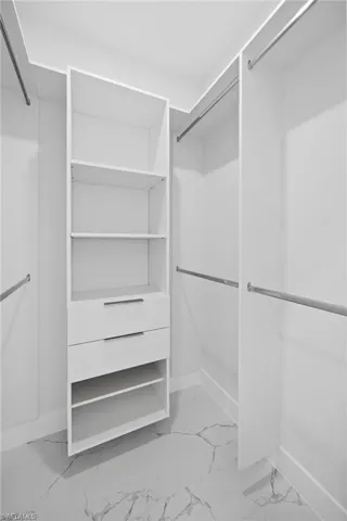 Spacious closet featuring light marble finish flooring