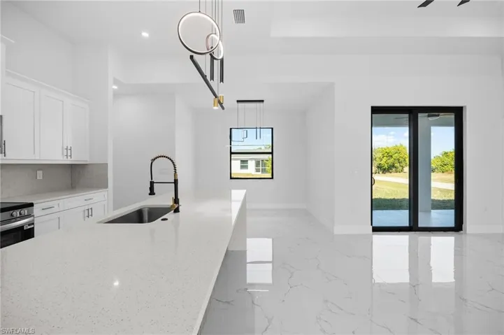 Kitchen featuring white cabinets, light stone counters, tasteful backsplash, light marble finish floors, and recessed lighting