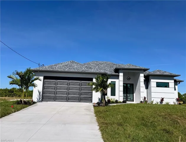 Modern Florida-style home featuring facade, driveway, a garage, and a front lawn