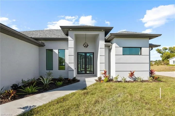 Entrance to property featuring a yard, stucco siding, and french doors