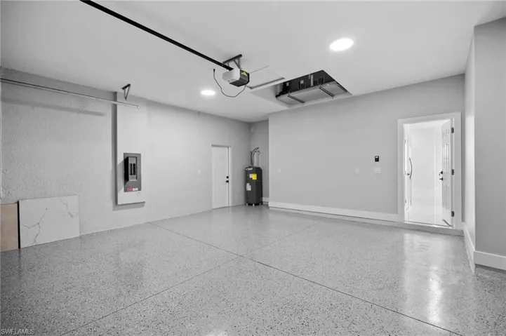 Garage featuring electric panel, recessed lighting, and water heater