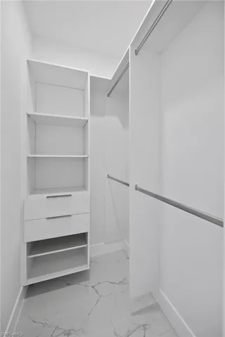 Walk in closet featuring light marble finish flooring