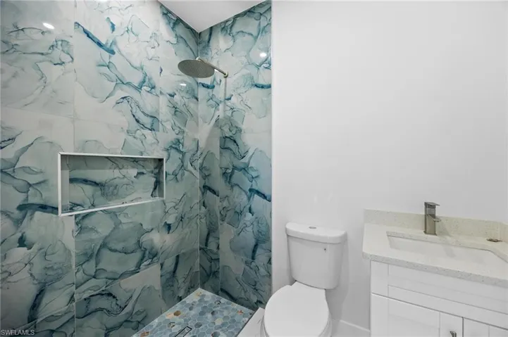 Full bathroom featuring a marble finish shower and vanity