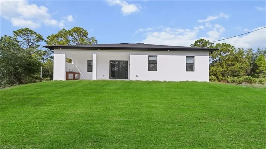 Rear view of property with a lawn, stucco siding, and a patio area
