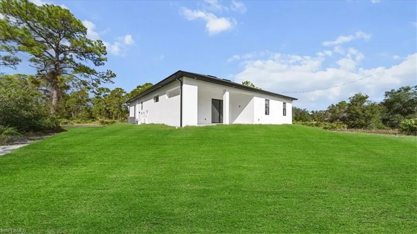 Rear view of house featuring a yard and stucco siding