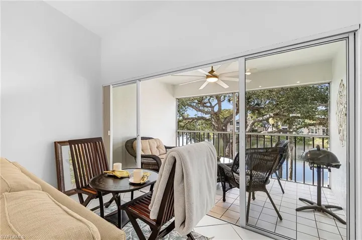 Dining area with light tile patterned flooring, a ceiling fan, and a water view