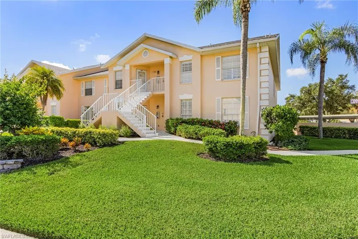 View of front of property featuring stucco siding, a front yard, and stairway